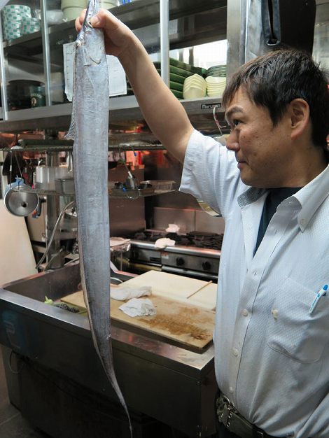 伊藤さんが持っているギラギラ新鮮な太刀魚は この後塩焼きになります